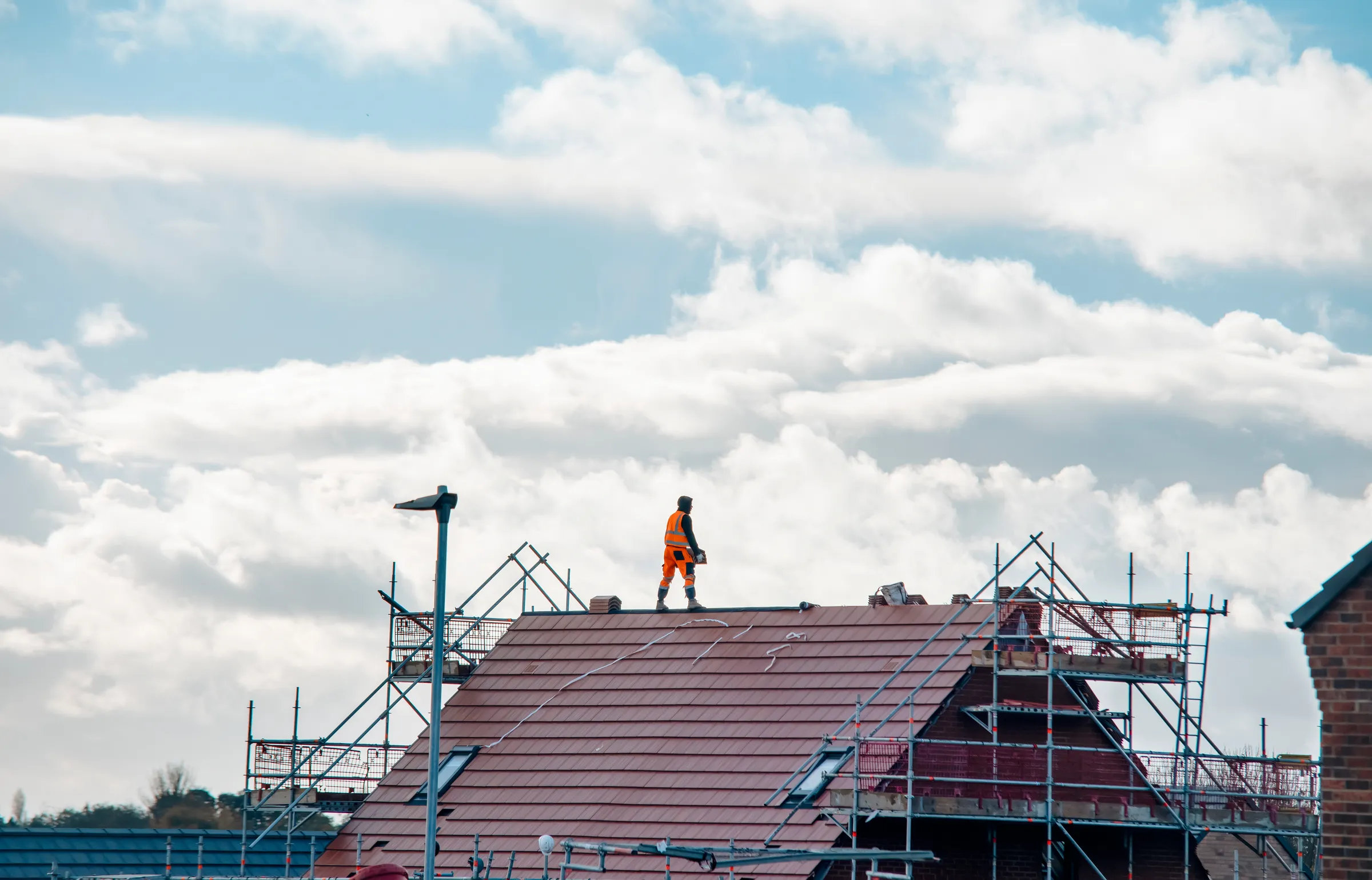 Roofer working on a large scaffolded pitched tile roof