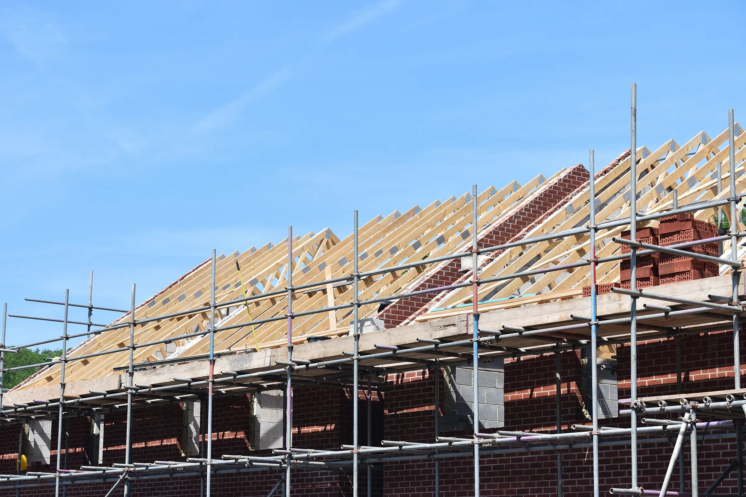 Timber roof trusses being installed on a scaffolded new-build house
